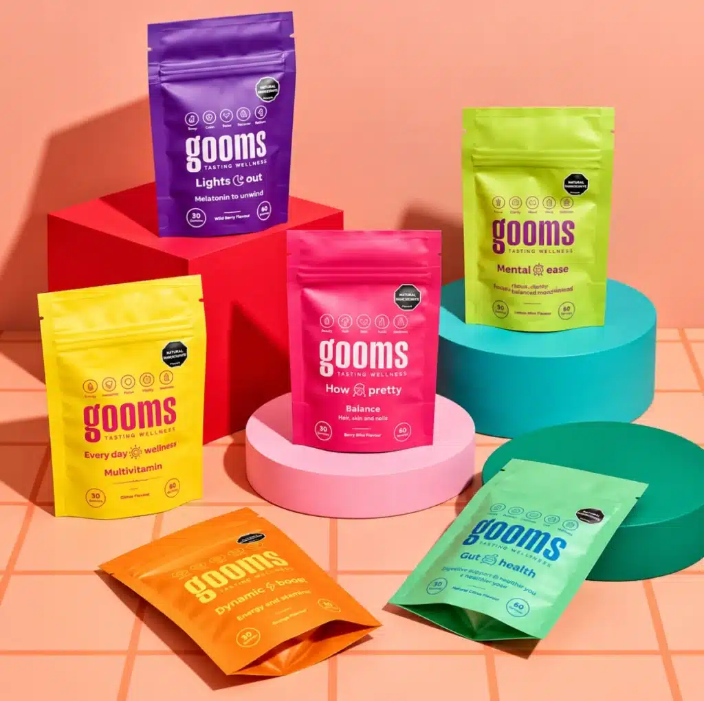 Colourful Gooms supplement pouches displayed on geometric platforms, showing a varied product range and consistent packaging design.